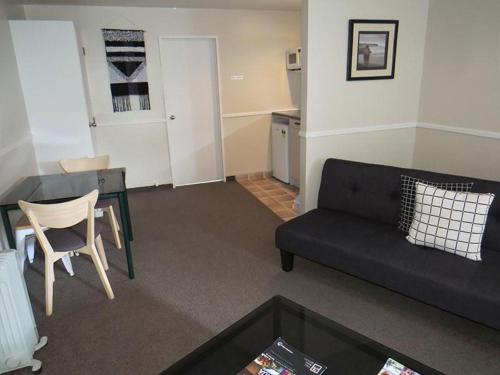 a living room with a black couch and a table at Pohutu Lodge Motel in Rotorua