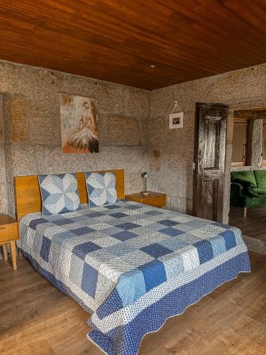 a bedroom with a bed with a blue and white checkered blanket at Casa do Cabeço de Boi by Refúgio ao Luar in Terras de Bouro
