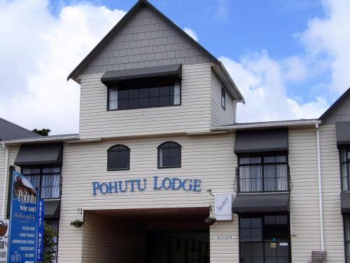 a white building with a sign on the front of it at Pohutu Lodge Motel in Rotorua