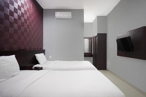 a hotel room with two beds and a tv at OYO 94785 Diana Homestay Syariah in Sunggal