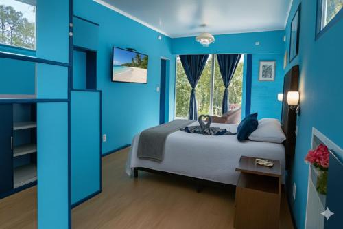 a blue bedroom with a bed and a window at Casa Gloria con Piscina - Jacuzzi exterior climatizada Relax Playa in Punta del Este