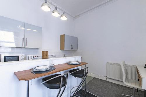 a kitchen with a wooden table and two chairs at Montague House Apartments in Llandudno