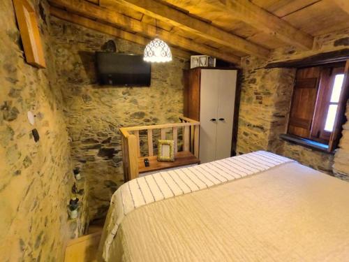 a bedroom with a bed in a stone wall at Casa do Talasnal by Refúgio ao Luar in Talasnal