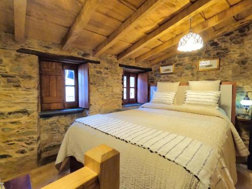 a bedroom with a large bed in a stone building at Casa do Talasnal by Refúgio ao Luar in Talasnal