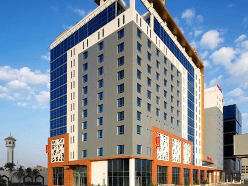 a tall building with a clock on the side of it at Adagio Jeddah City Center in Jeddah
