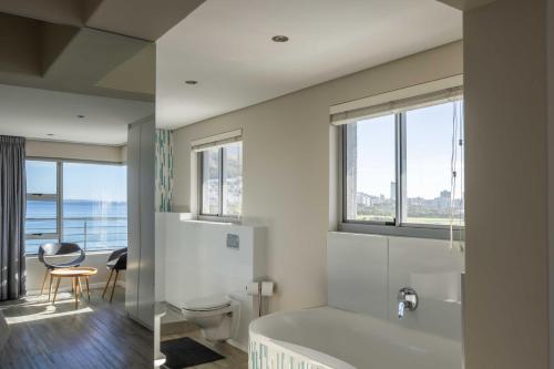 bagno con vasca, servizi igienici e finestre di Ocean View Properties - Apartment 701 a Città del Capo