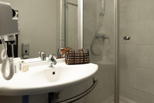 um banheiro com pia e chuveiro em Hôtel Akena Caudry Cambrai em Caudry