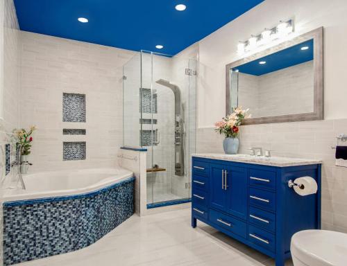 a bathroom with a blue ceiling and a tub and sink at Tejsvhi Hotel Aerocity in Jāmb