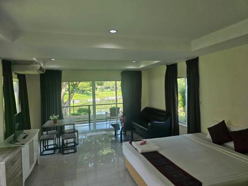a bedroom with a bed and a living room with a balcony at Kaengkrachan Diamond Green Resort in Ban Song Phi Nong