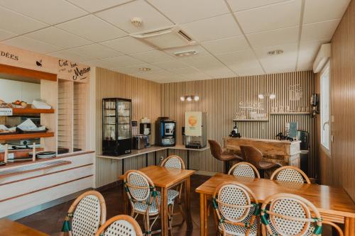 un restaurant avec des tables et des chaises en bois et un comptoir dans l'établissement Hôtel Akena Caudry Cambrai, à Caudry