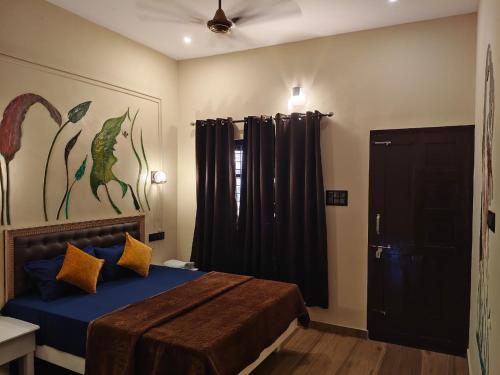 1 dormitorio con 1 cama con sábanas azules y almohadas amarillas en Leaf Garden Retreat, en Varkala