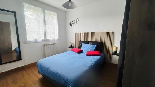 巴尔雅克Chez Nana - Maison dans le Gard的一间卧室配有蓝色的床和两个红色枕头