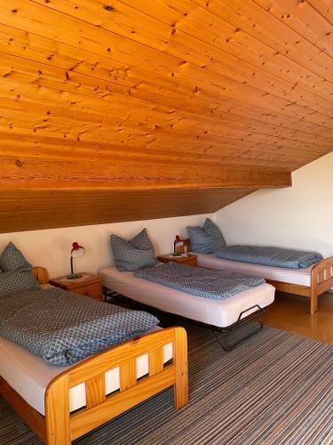 three beds in a room with a wooden ceiling at Esingerhof in Laufen
