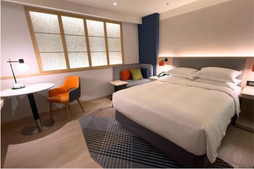 a bedroom with a bed and a desk and a table at Holiday Inn Express Taipei Train Station by IHG in Taipei