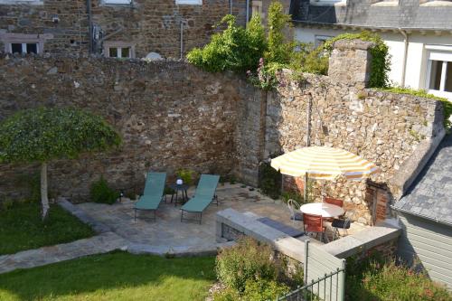a patio with a table and chairs and an umbrella at Appartement d'exception - proche de la mer in Saint-Brieuc