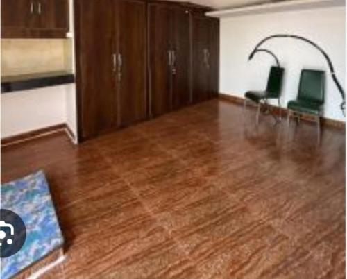a room with two green chairs and a wooden floor at Vinayak Homestay in Mathura
