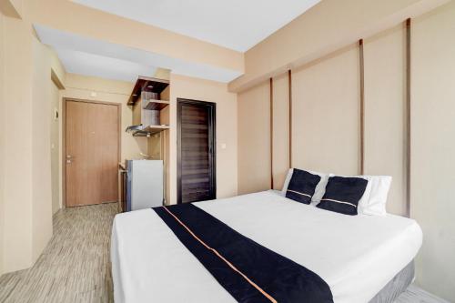 une chambre avec un grand lit blanc avec des oreillers bleus dans l'établissement OYO 94838 Dahoma Tower, à Tjikuda Tiga