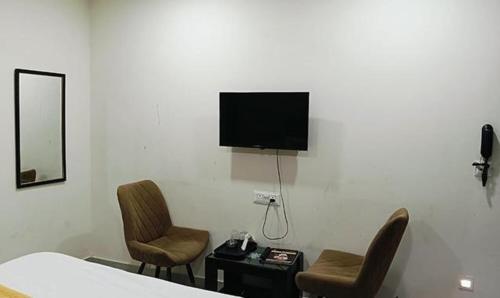 1 dormitorio con 2 sillas y TV en la pared en FabHotel Kalka Residency, en Nueva Delhi