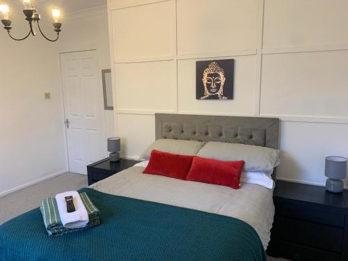 ein Schlafzimmer mit einem Bett mit zwei roten Kissen in der Unterkunft Springfield Apartment - Train to Glasgow or Edinburgh - Private Parking & Wifi in Airdrie