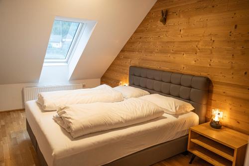 una cama en una habitación con una pared de madera en Dorfplatzl Suite, en Hohentauern