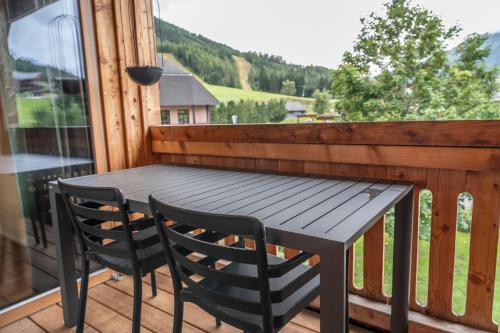 Una mesa de madera y dos sillas en un balcón. en Dorfplatzl Suite, en Hohentauern