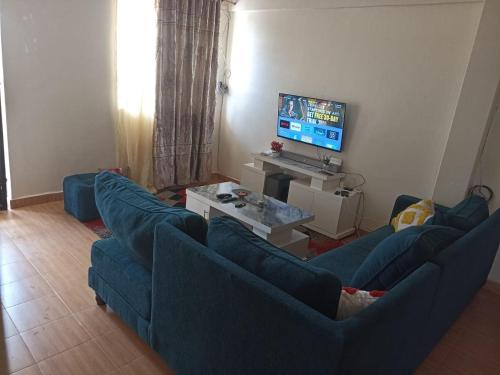 a living room with two blue couches and a television at Jay homes in Kakamega