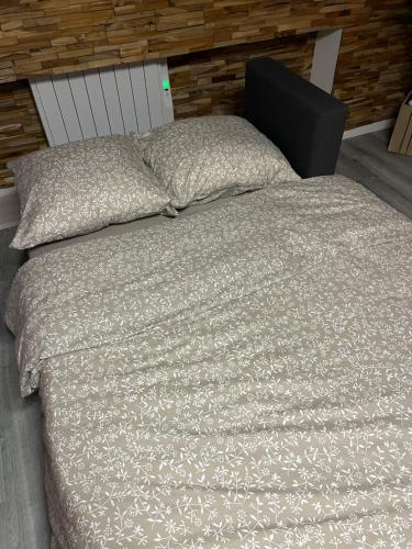 1 cama con edredón gris y 2 almohadas en Le Refuge du Cerf, en Bouillon