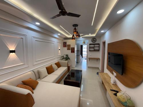 a living room with a white couch and a tv at Krishna Heights in Karnal