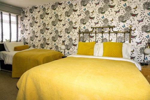 two beds in a room with floral wallpaper at Kenley Hotel in Blackpool