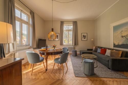 Teinach Suites - Villa Wilhelmshöhe في باد تايناخ-تسافلشتاين: غرفة معيشة مع أريكة وطاولة وكراسي