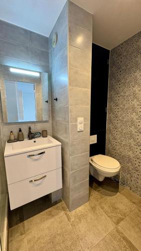 a bathroom with a white sink and a toilet at Le Panorama, confortable appartement - accès direct à la plage in Bernières-sur-Mer