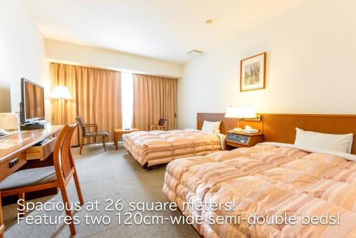 a hotel room with two beds and a desk at Tendo Central Hotel in Tendo