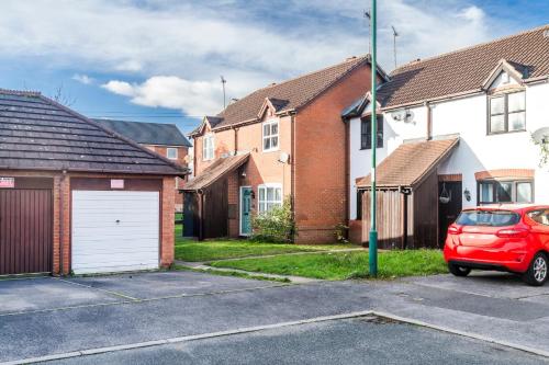 a red car parked in a parking lot in front of houses at 2BR House Secure Parking For Short and Long Stays Private Garden and Netflix, Nottingham in Nottingham