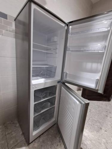 Cosdarl Homes في Midie: ثلاجة فارغة وبابها مفتوح في المطبخ
