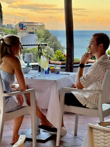 a man and woman sitting at a table eating food at Hotel La Pergola in Amalfi