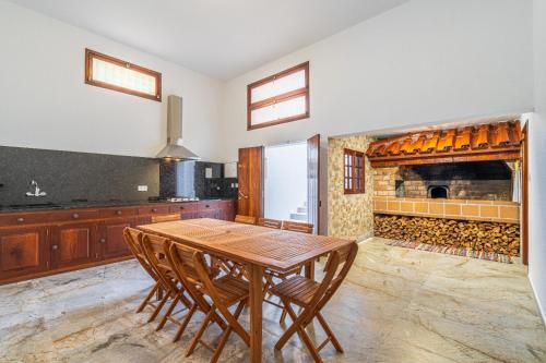 a kitchen with a wooden table and a fireplace at Casa do Vale in São Vicente