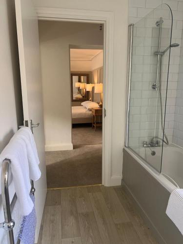 a bathroom with a shower and a tub and a bedroom at The OXTED high street studio in Oxted