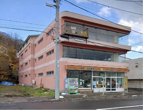 a pink building with a balcony on top of it at World Inn むろらん仲間の家 in Muroran