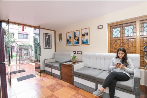 杜尔加布尔FabHotel Sriya - City Center, Durgapur的坐在沙发上的女人看着她的手机