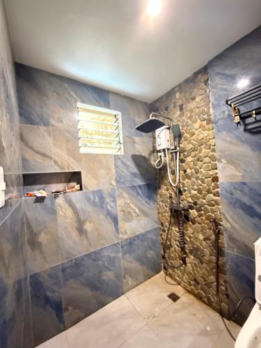 een badkamer met douche met een stenen muur bij R&C Transient House in El Nido