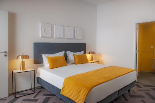 um quarto com uma cama grande com travesseiros amarelos em Glória Suites Hotel em Lisboa