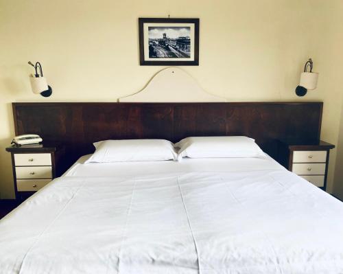 Un dormitorio con una gran cama blanca con dos mesitas de noche. en Hotel Max, en Aversa