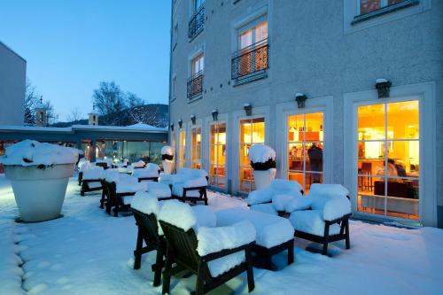 um grupo de cadeiras cobertas de neve em frente a um edifício em ARCOTEL Castellani Salzburg em Salzburgo