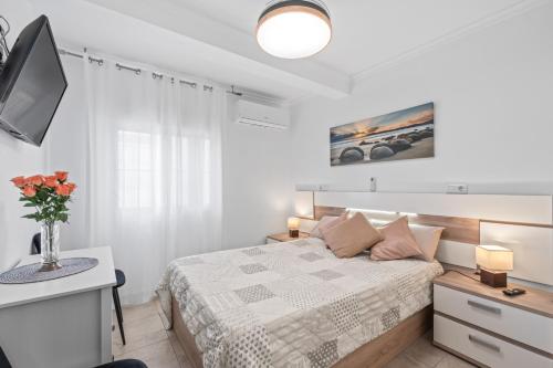a white bedroom with a bed and a tv at Geani in La Marina