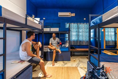 2 hommes assis dans une chambre avec lits superposés dans l'établissement Zostel Alleppey, à Alappuzha