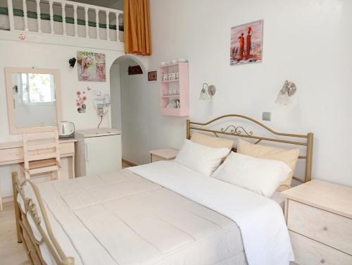 Un dormitorio con una cama blanca y un escritorio. en The Best, en Perissa