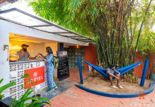 Un hombre sentado en una hamaca afuera de un restaurante. en Zostel Alleppey, en Alleppey