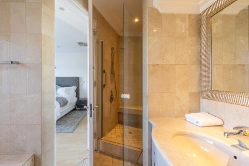 een badkamer met een wastafel en een glazen douche bij Atlantic Sky Penthouses - Breathtaking Views in Kaapstad