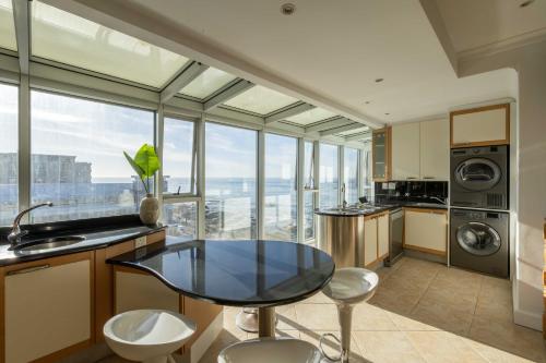een keuken met een glazen tafel en een aantal stoelen bij Atlantic Sky Penthouses - Breathtaking Views in Kaapstad