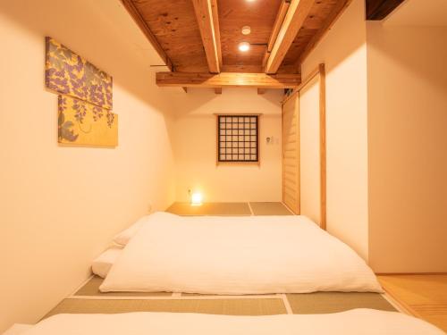 ひとあかり 東山 Hitoakari Higashiyama-A Warm and Modern Machiya Stay في Shimmachidōri: غرفة نوم بها سرير في الغرفة